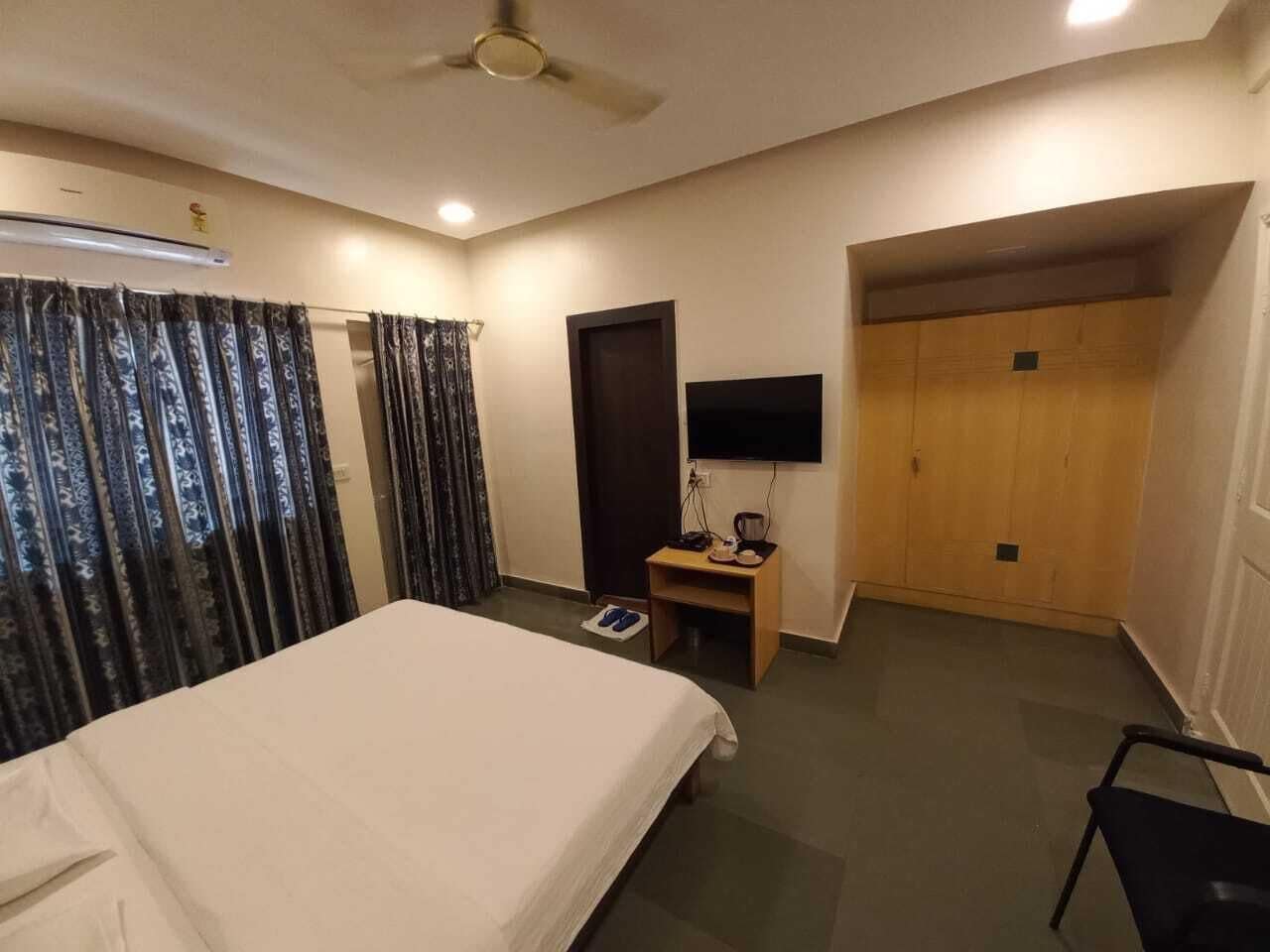 Una habitación de hotel con una cama, un escritorio con una silla, un televisor y un armario.
