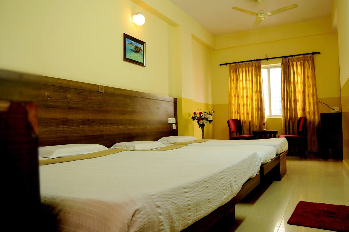 A hotel room with a large bed, a desk, a chair, and a window with curtains.