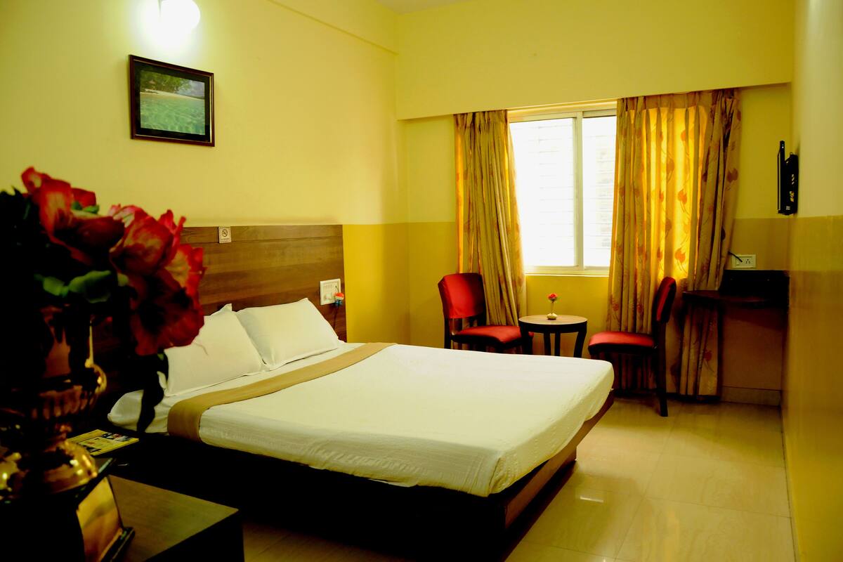 A hotel room with a bed, a desk, a chair, and a window with curtains.