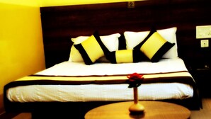 A hotel room with a bed, a bedside table with a vase, and a wall socket.
