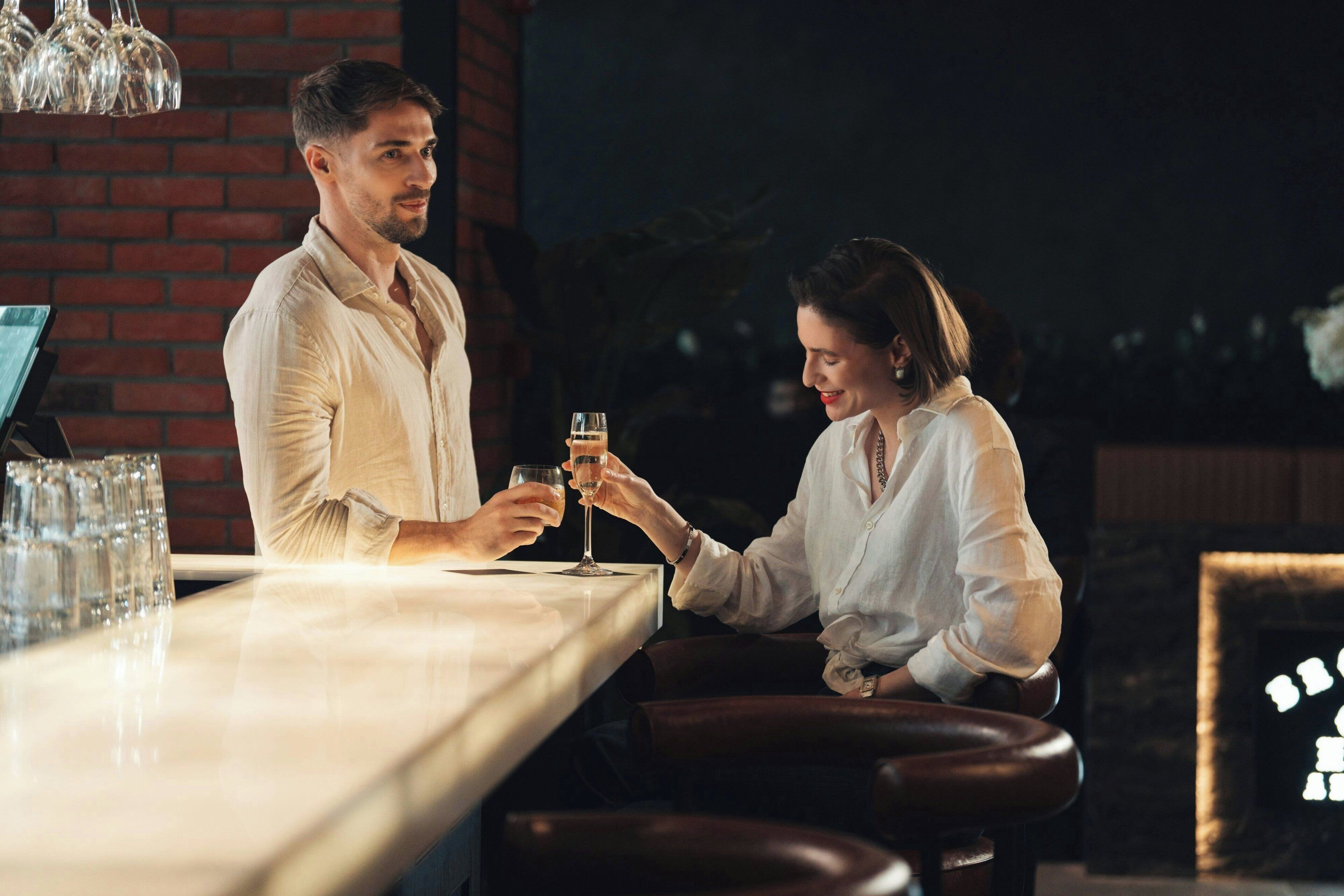 A bar area with a brick wall, a long counter, and several glasses on the left.