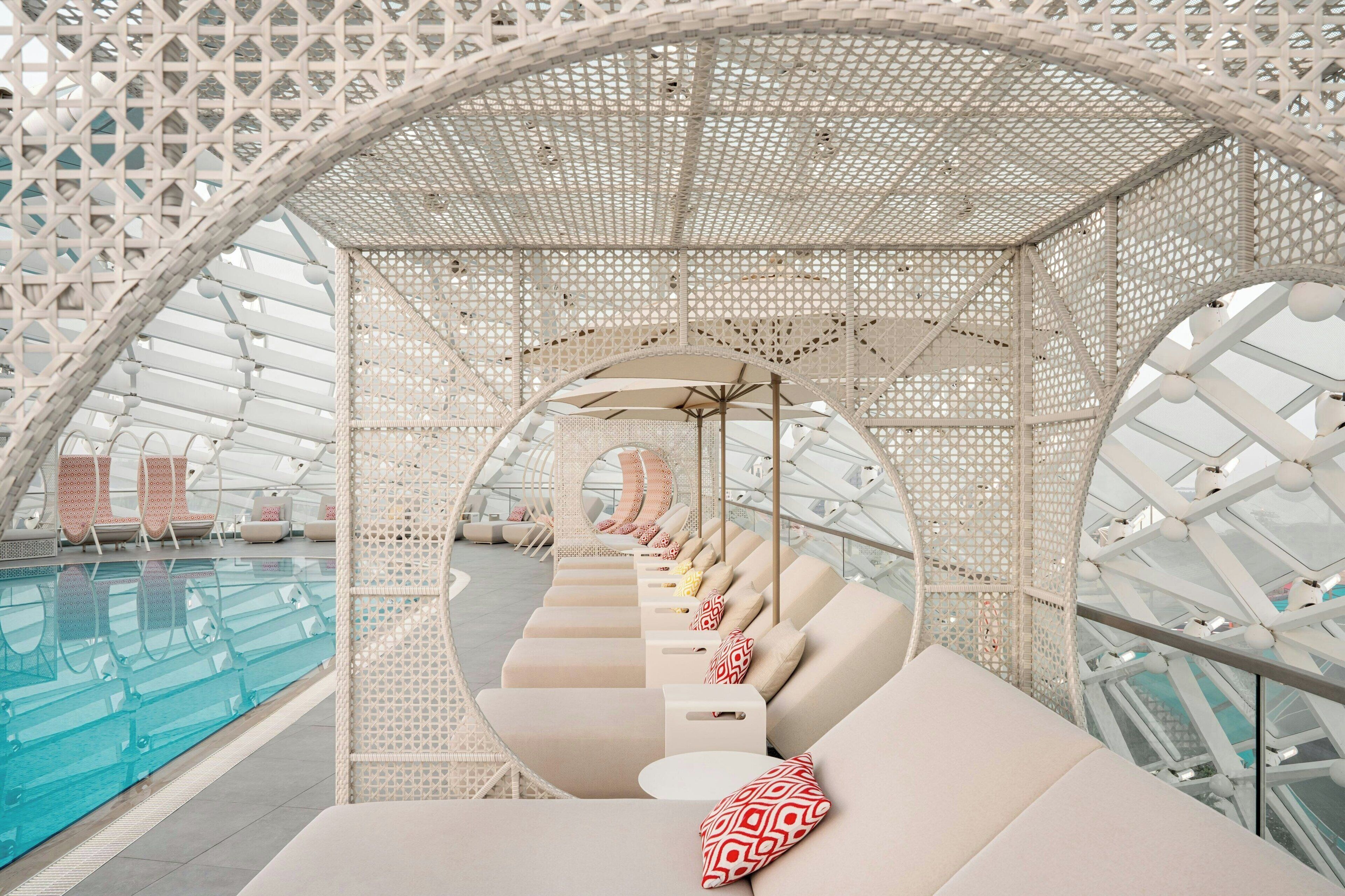 A poolside lounge with a series of sun loungers and a glass-enclosed pool.