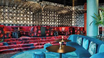 A modern lounge area with a blue sofa, round tables, and a patterned wall.