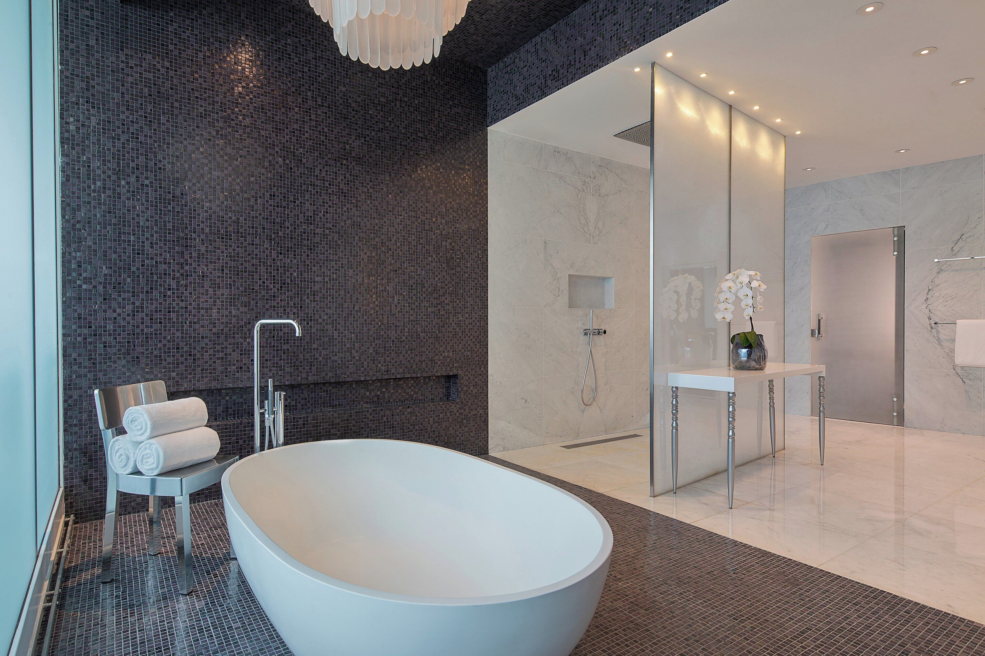 Un baño moderno con una bañera independiente, cabina de ducha con paredes de vidrio y tocador blanco con espejo.