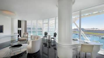 A modern interior with a glass table, seating, and a view of a bridge and water.