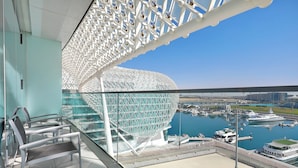 Een modern gebouw met een opvallende, bolvormige structuur en een jachthaven met boten op de achtergrond.