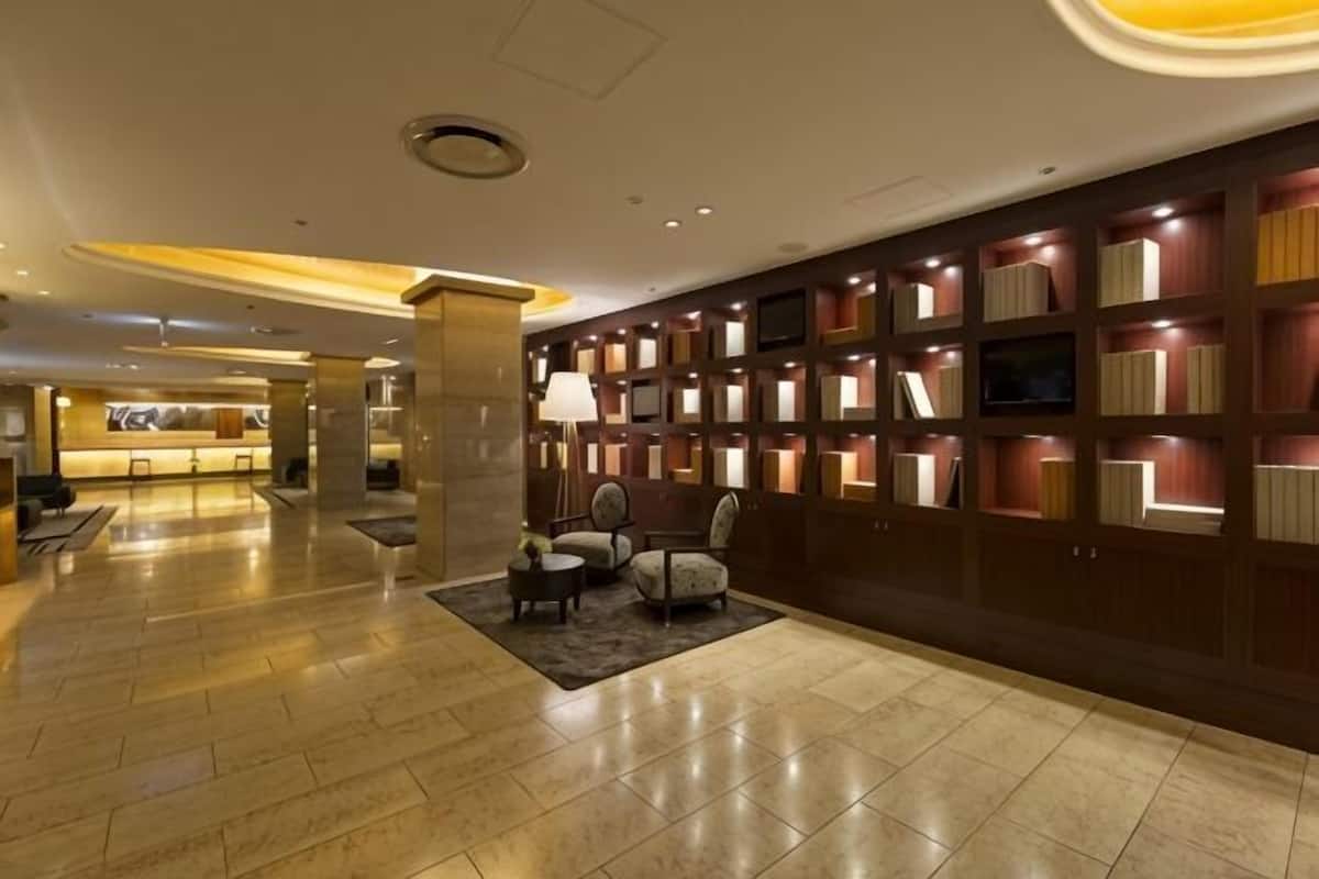 A hotel lobby with a reception desk, seating area, and a wall of bookshelves.