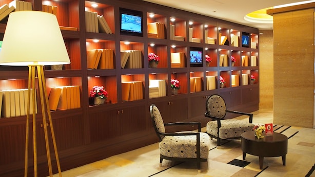 A lobby with a wall of bookshelves, two patterned chairs, a floor lamp, and a small round table. - Shibuya Tobu Hotel (Tokyo)
