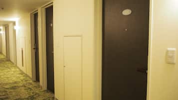 A hotel hallway with multiple doors, some with visible door numbers, and a carpeted floor.