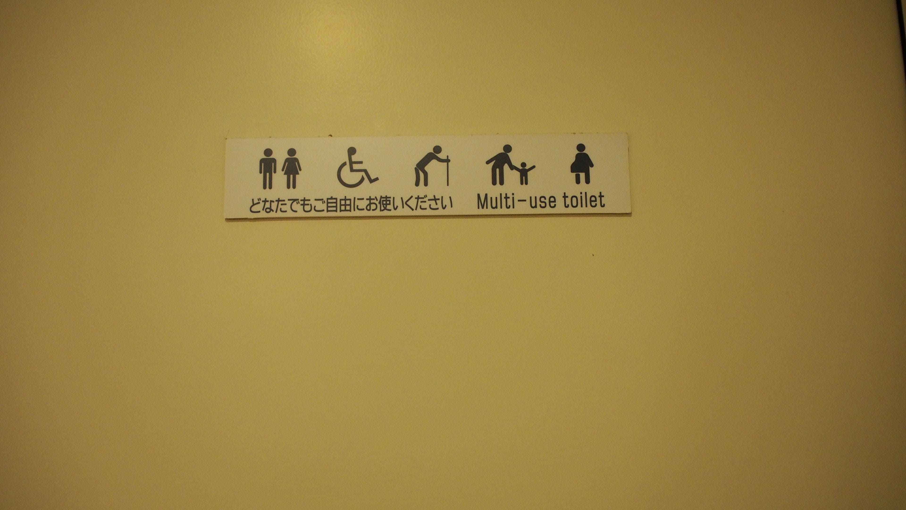 A multi-use toilet sign with symbols for men, women, wheelchair users, and children.