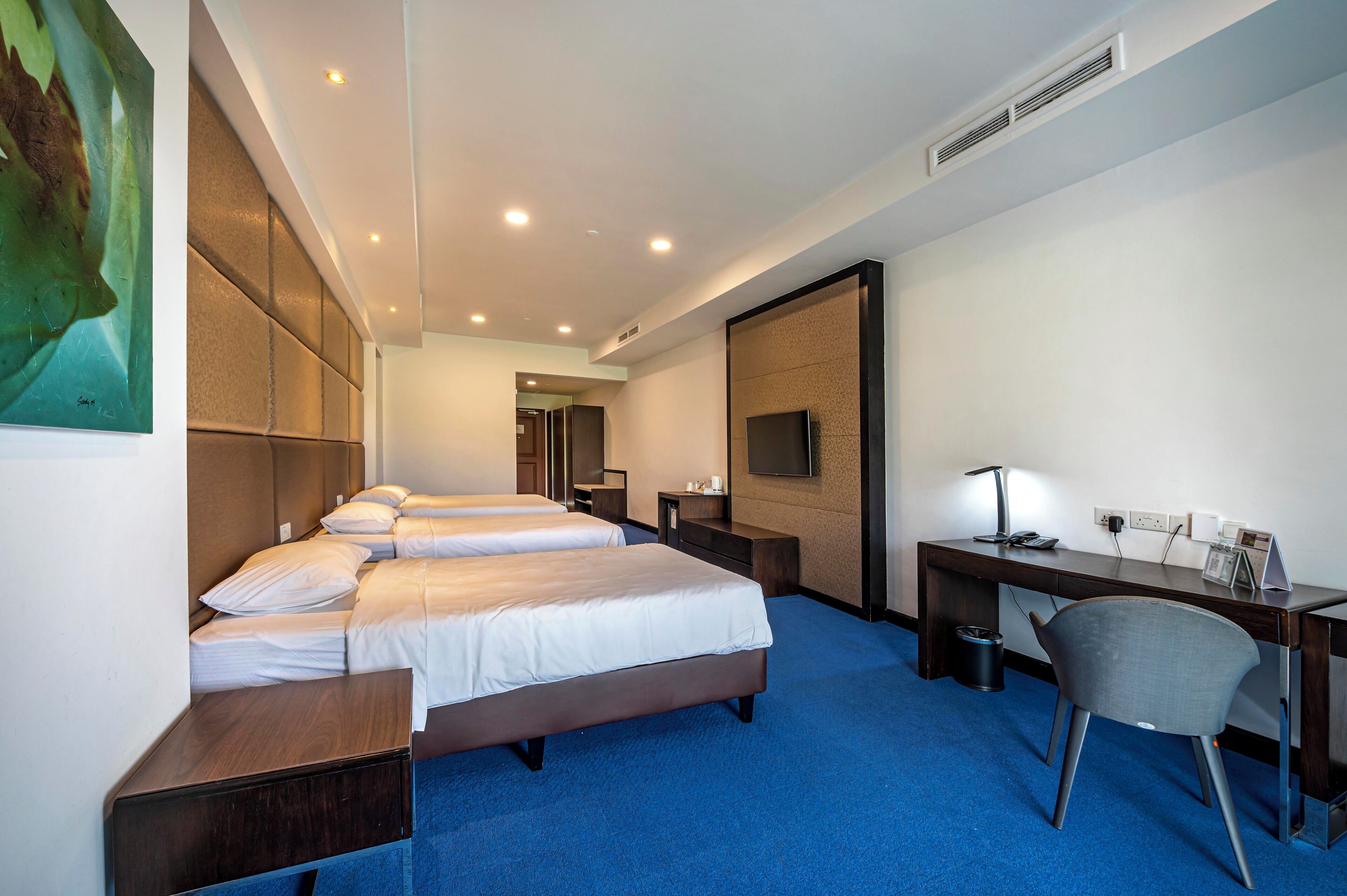 Habitación de hotel con dos camas, un escritorio, una silla y una televisión.