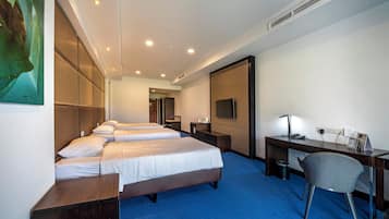Habitación de hotel con dos camas, un escritorio, una silla y una televisión.