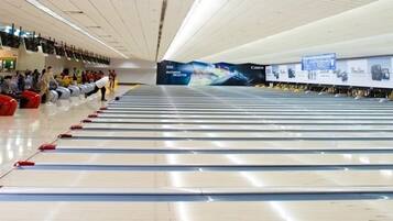 A bowling alley with multiple lanes, advertisements for Canon and LG, and a person bowling.