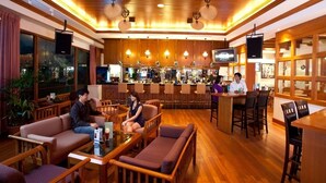 A bar area with wooden flooring, cushioned seating, and a bar counter. - Orchid Country Club (Singapore)