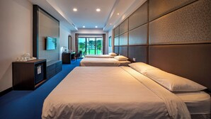 A hotel room with two beds, a desk, and a view of the outdoors. - Orchid Country Club (Singapore)