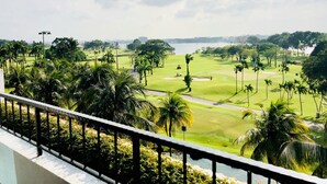 A golf course with palm trees and a water body in the background. - Orchid Country Club (Singapore)
