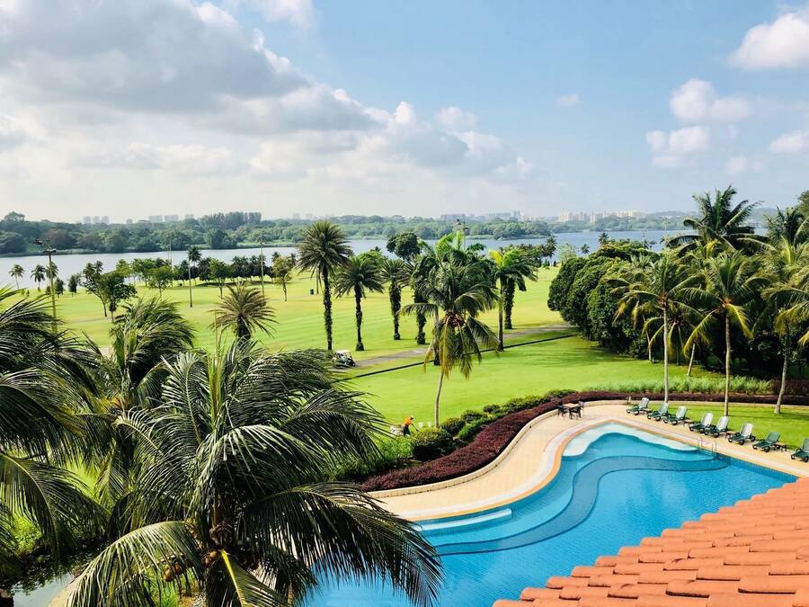 Vista a la piscina con una vista despejada de un campo de golf, palmeras y un horizonte urbano distante.