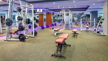 A gym with various weightlifting equipment, benches, and a mirrored wall.