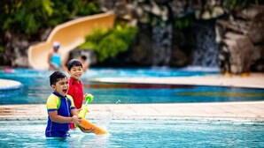 A swimming pool with a water slide in the background. - Orchid Country Club (Singapore)