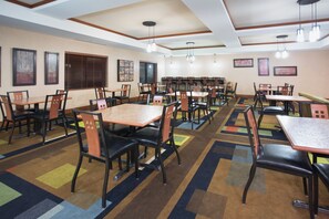 Un comedor de hotel con varias mesas y sillas dispuestas en filas.