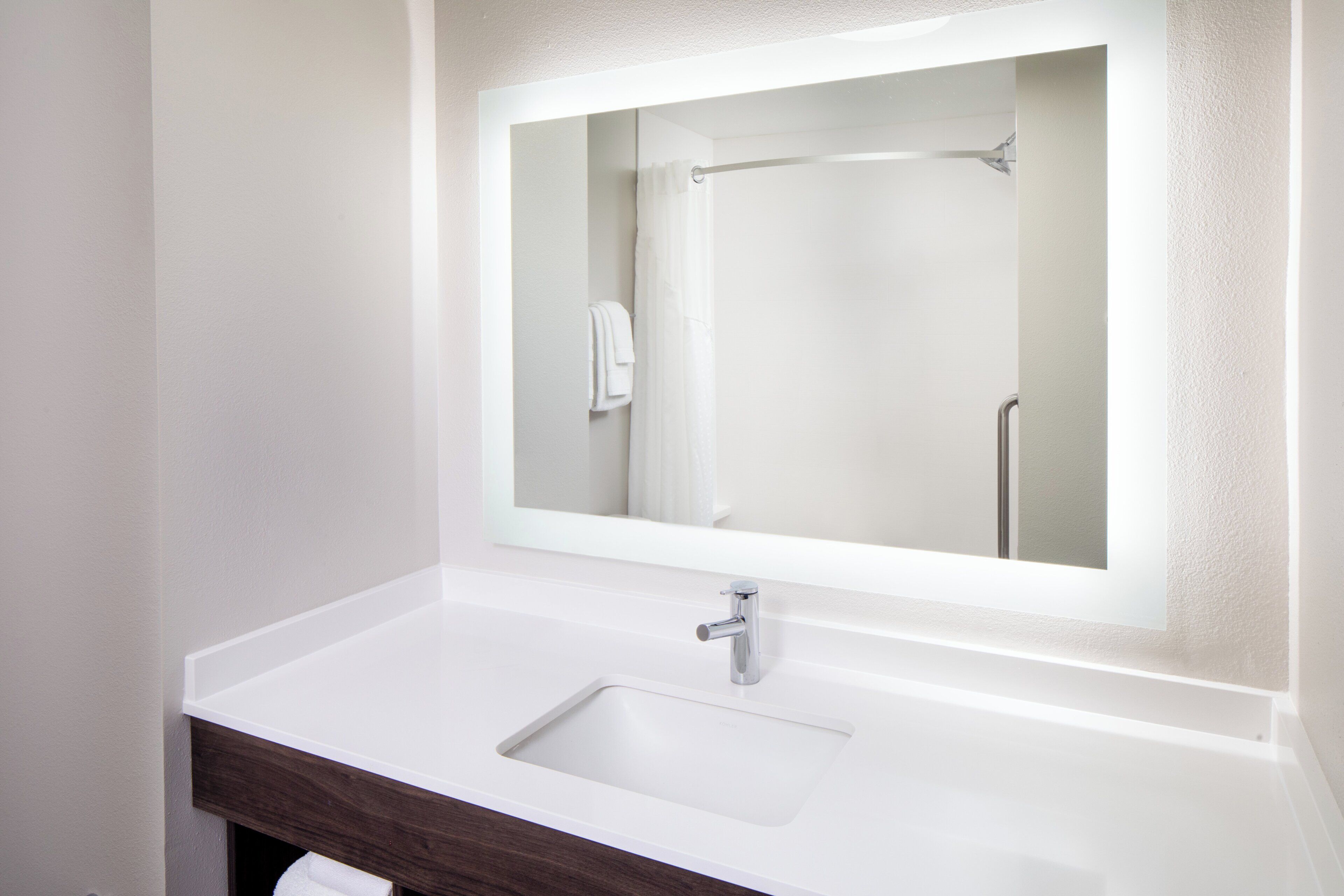 A bathroom with a white sink, a mirror, and a shower.
