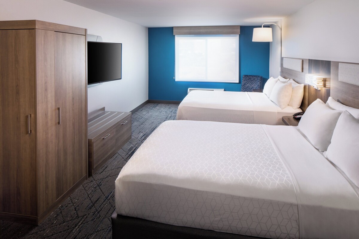Une chambre d’hôtel avec deux lits, une armoire, un téléviseur à écran plat et une fenêtre donnant sur un paysage agréable.