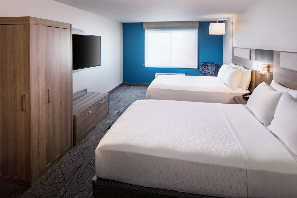 A hotel room with two beds, a wardrobe, a flat-screen TV, and a window with a view.