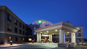 Un hotel Holiday Inn Express con entrada techada y fachada de piedra.