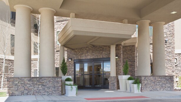 A building entrance with a stone facade, large columns, and a glass door. - Holiday Inn Express & Suites Los Alamos Entrada Park by IHG (Los Alamos)