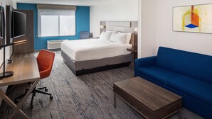 A hotel room with a bed, a desk with a chair, a blue sofa, and a TV. - Holiday Inn Express & Suites Los Alamos Entrada Park by IHG (Los Alamos)