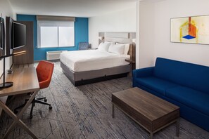 Une chambre d’hôtel avec un lit, un bureau et une chaise, un canapé bleu et un téléviseur.