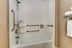 Baño con bañera, barras de apoyo, ducha y perchero.