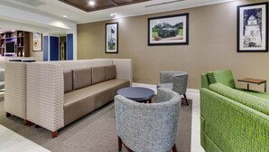 A modern lounge area with a sofa, armchairs, and a small table.