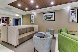 A modern lounge area with a sofa, armchairs, and a small table.