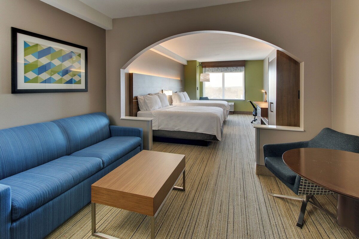 Habitación de hotel con sofá, cama, mesa y un espejo grande.
