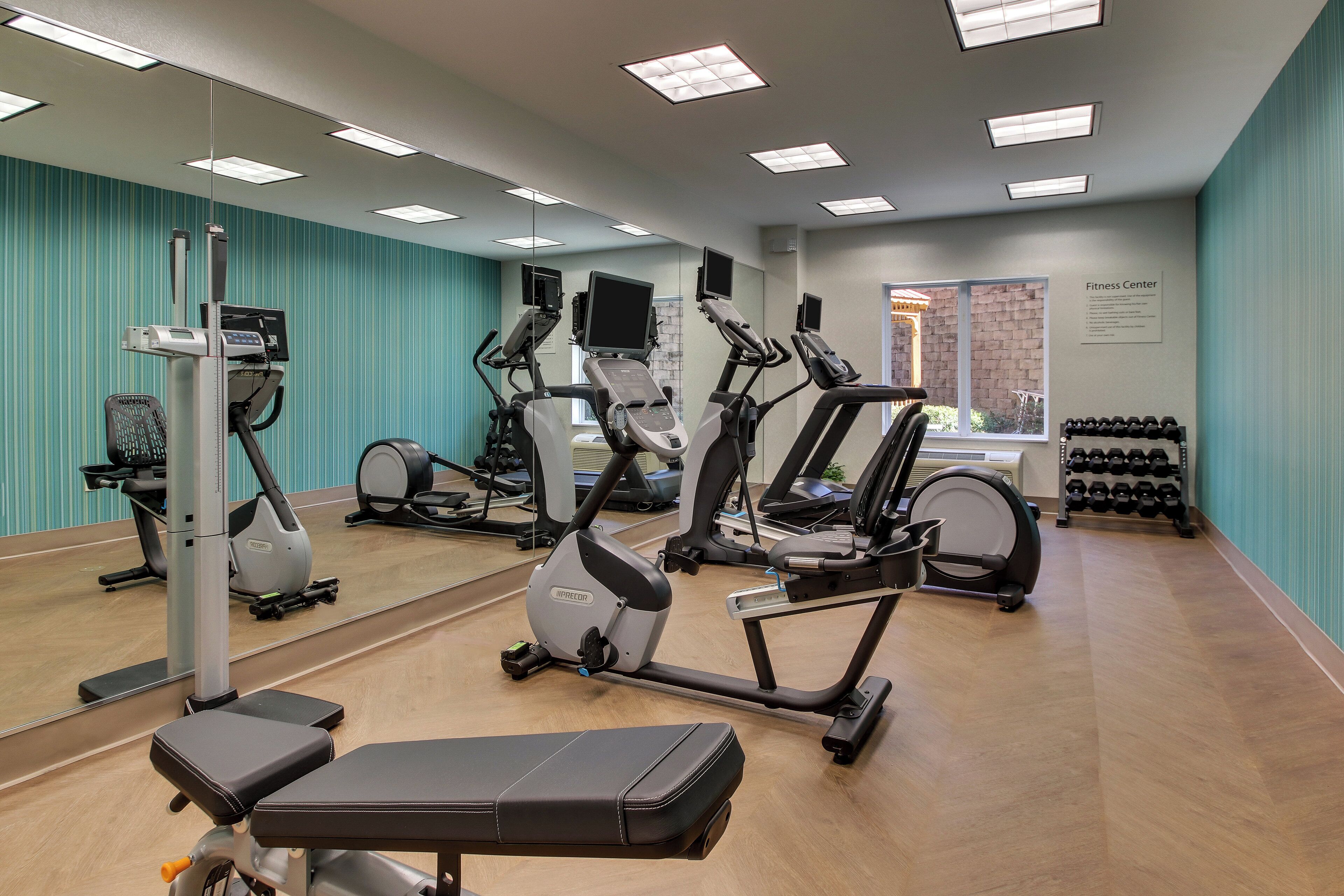 A fitness center with cardio machines, a bench, and a wall-mounted mirror.