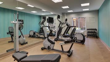 A fitness center with cardio machines, a bench, and a wall-mounted mirror.