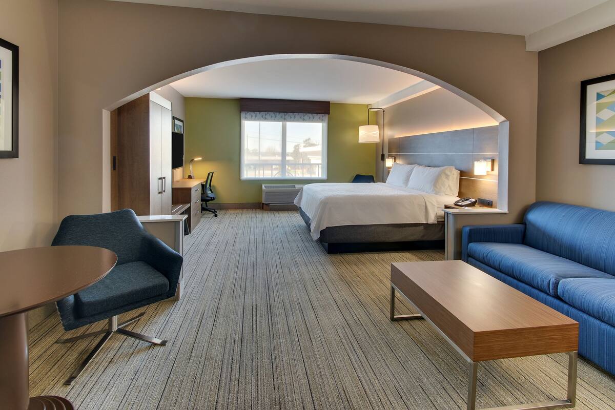 Une chambre d’hôtel avec un lit, un canapé, un bureau et une chaise.