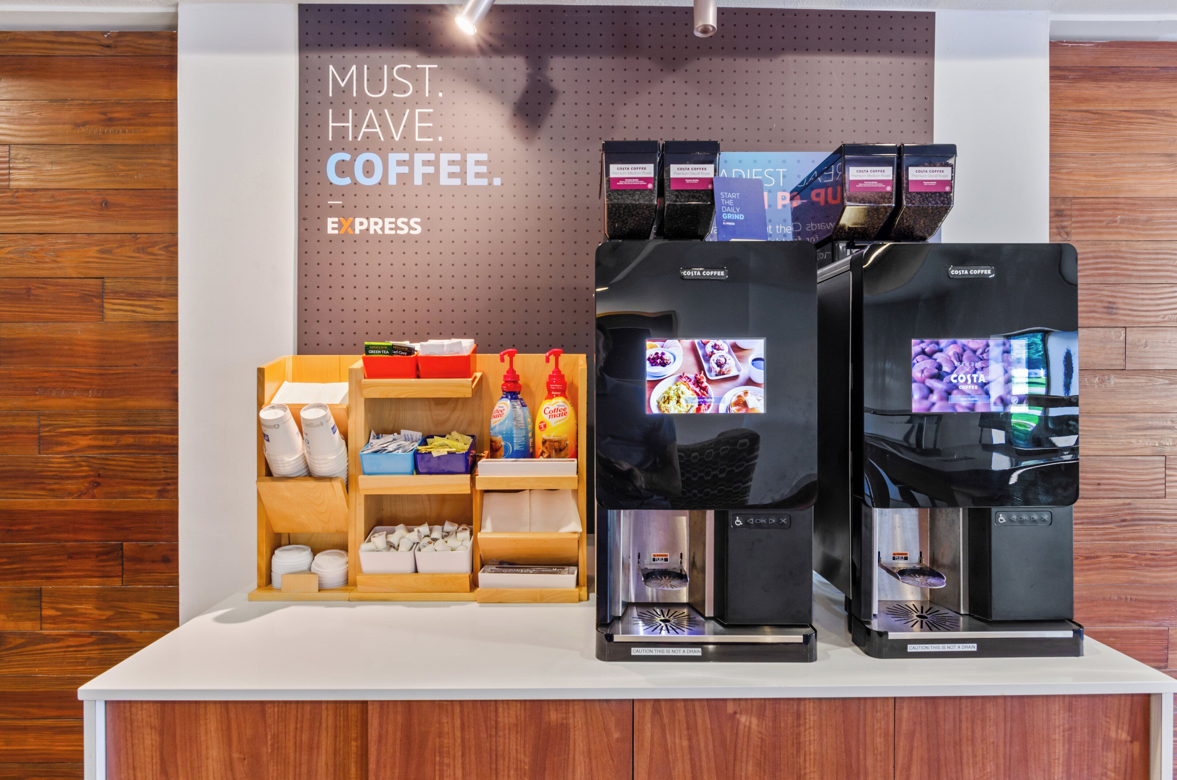 Dos máquinas de café con un estante de cápsulas y una exhibición de productos relacionados con el café.