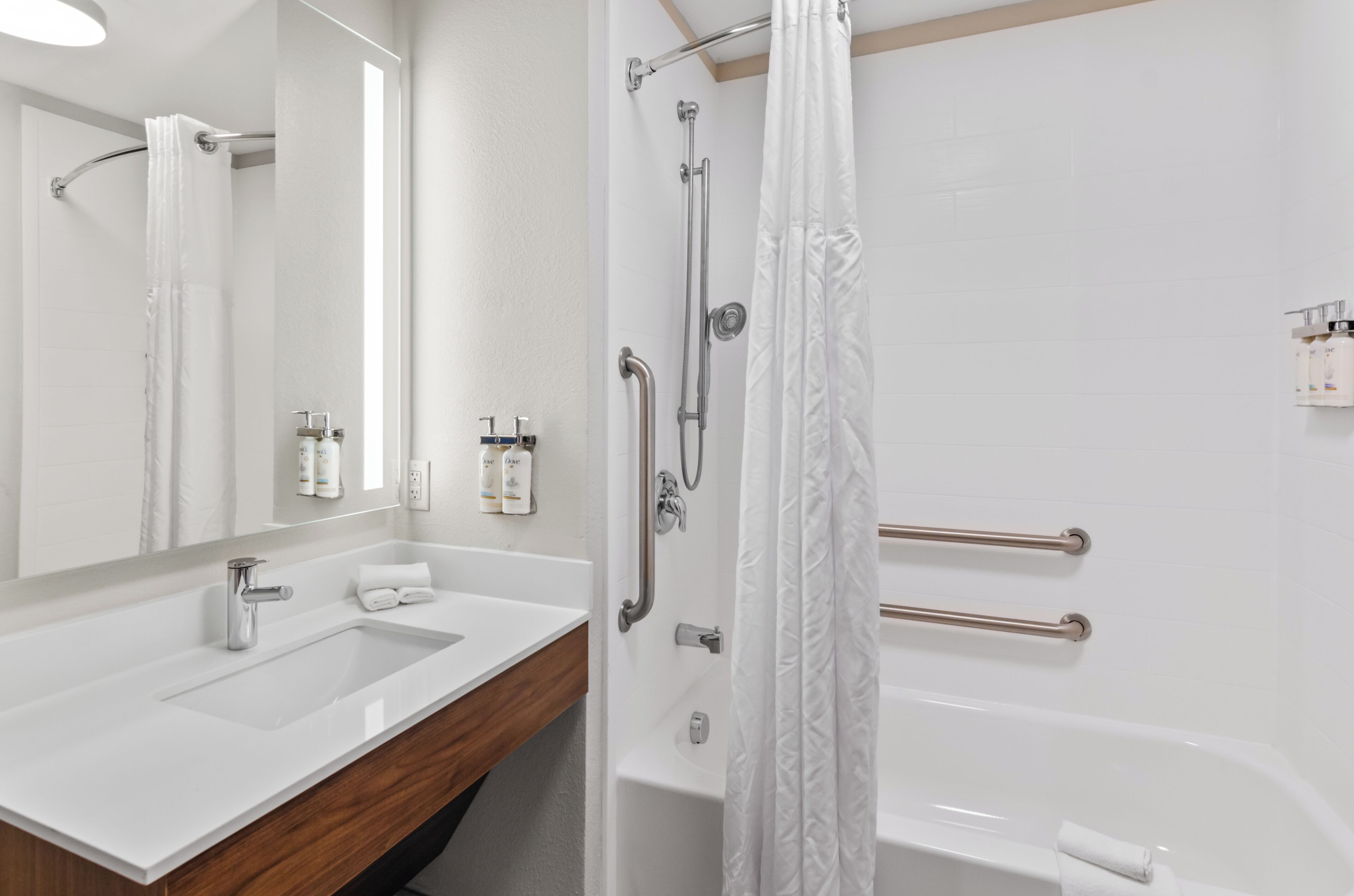 A bathroom with a white sink, mirror, and shower.
