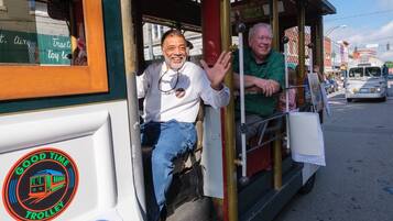 A trolley with a "Good Time Trolley" logo, a man in a white shirt, and another man in a green shirt.