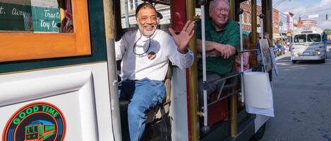 A trolley with a "Good Time Trolley" logo, a man in a white shirt, and another man in a green shirt.