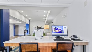 A hotel reception desk with a computer monitor, a desk lamp, and two chairs. - Holiday Inn Express Hotel & Suites Mount Airy by IHG (Mount Airy)