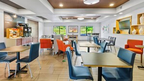 Un café moderno con techo de madera, varias mesas y sillas, y una estación de café.
