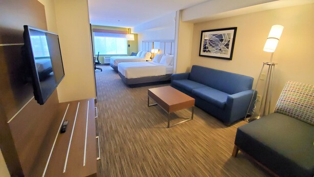 Una habitación de hotel con televisión, sofá, cama, escritorio y lámpara.