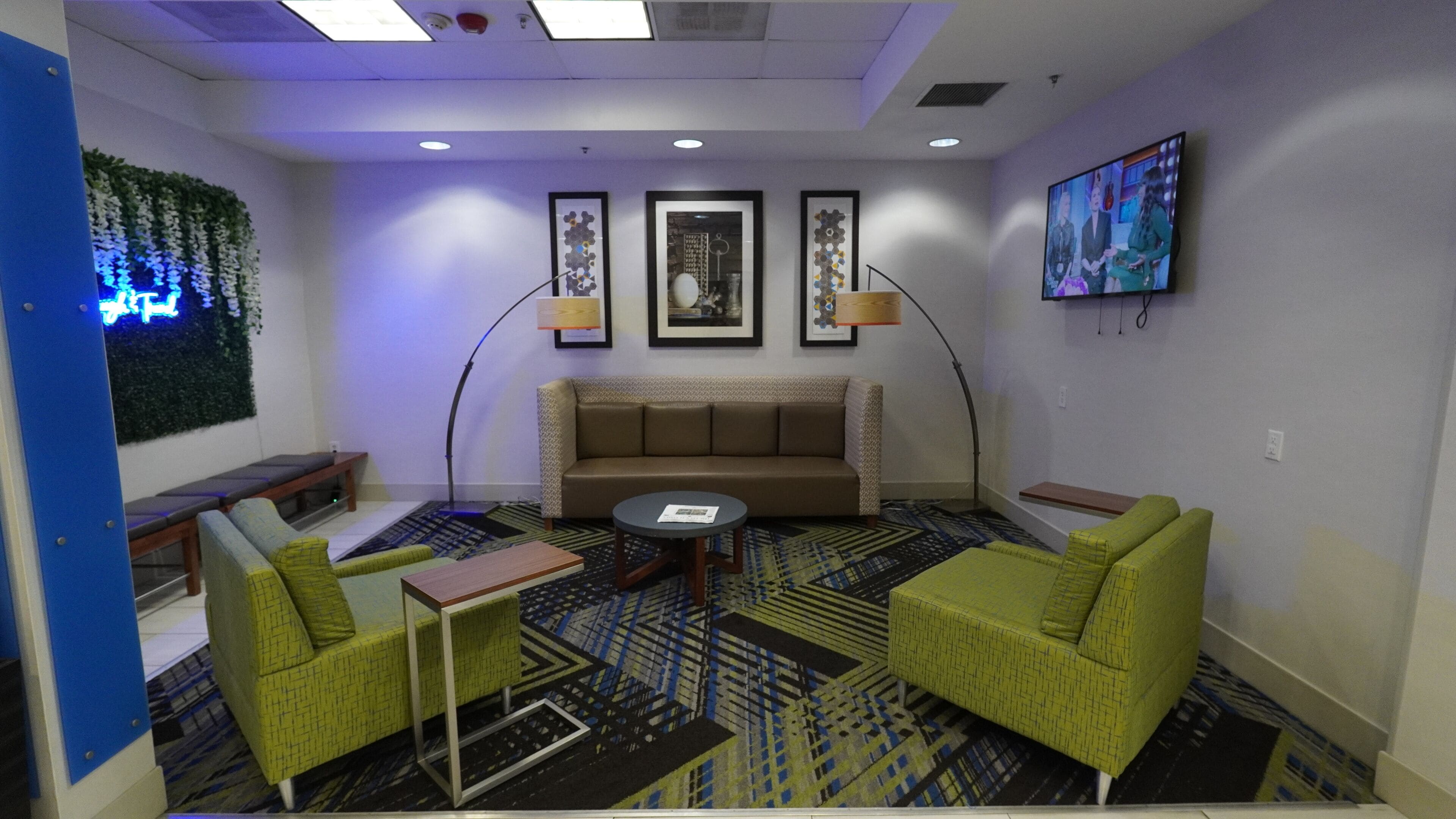 A modern lounge area with a sofa, two armchairs, a coffee table, and a patterned carpet.