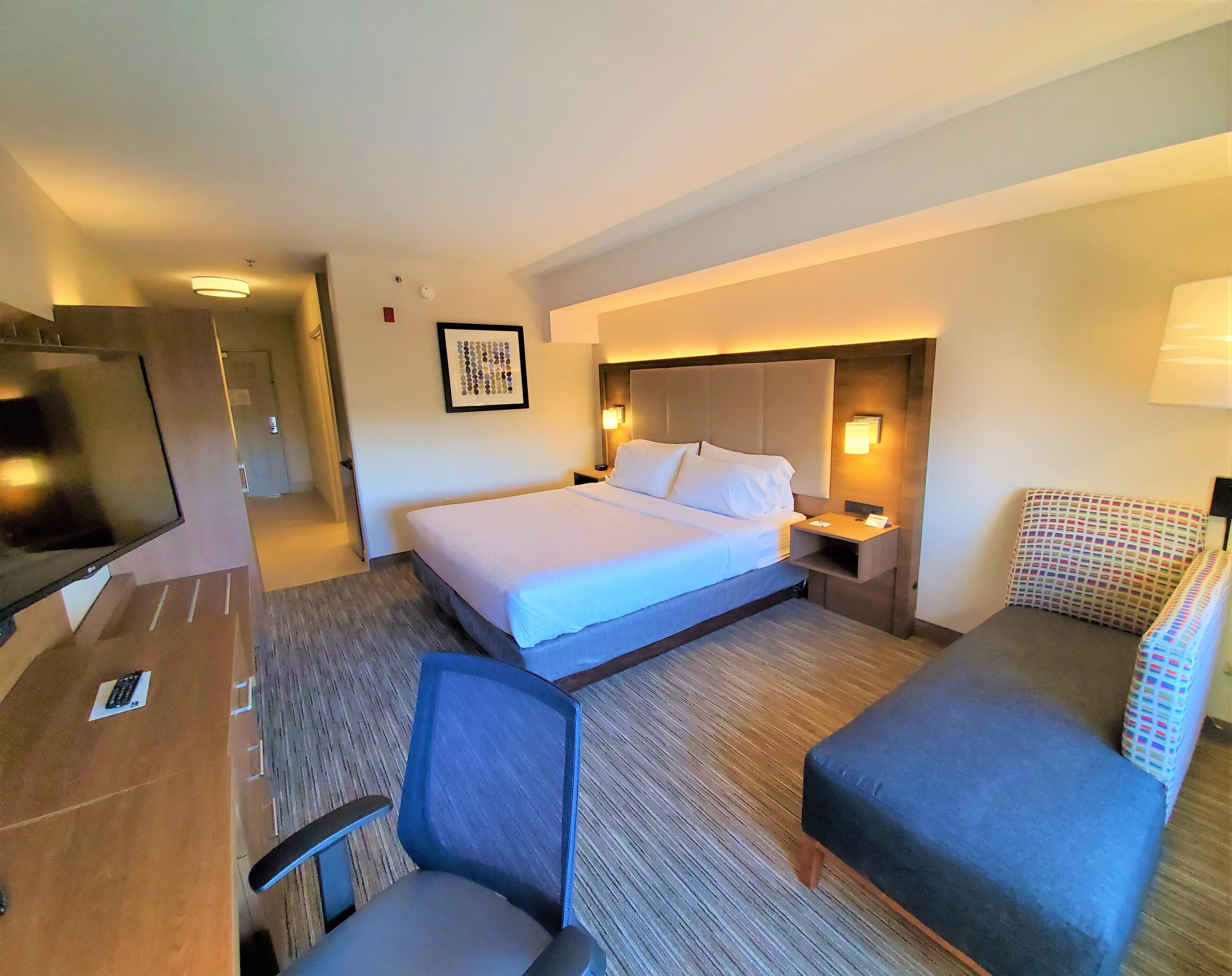 Une chambre d’hôtel équipée d’un lit, d’un bureau, d’une chaise, d’une télévision et d’une table de chevet.