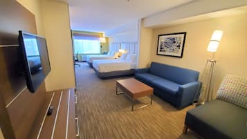 Une chambre d’hôtel équipée d’une télévision, d’un canapé, d’un lit, d’un bureau et d’une lampe.