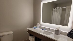 Un baño moderno con inodoro, lavamanos y espejo.