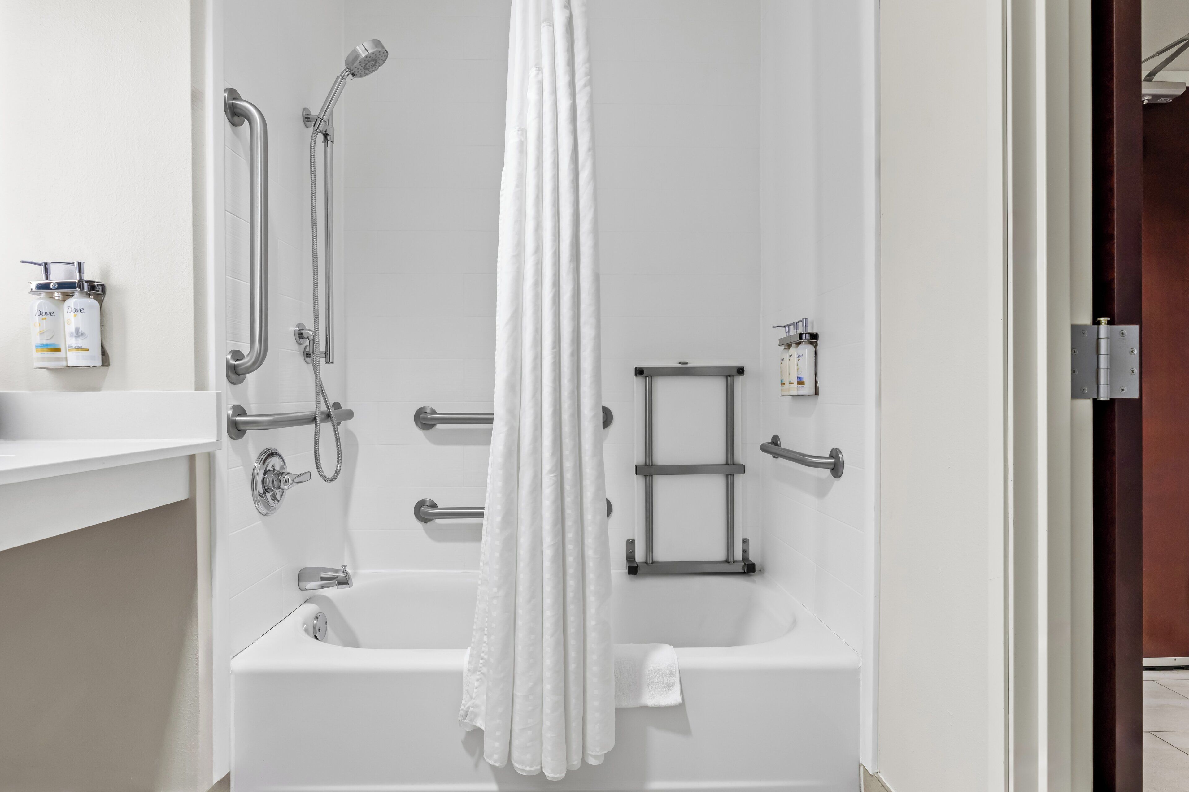 Een moderne badkamer met een witte badkuip, handgrepen, een douchekop en een handdoekhouder.